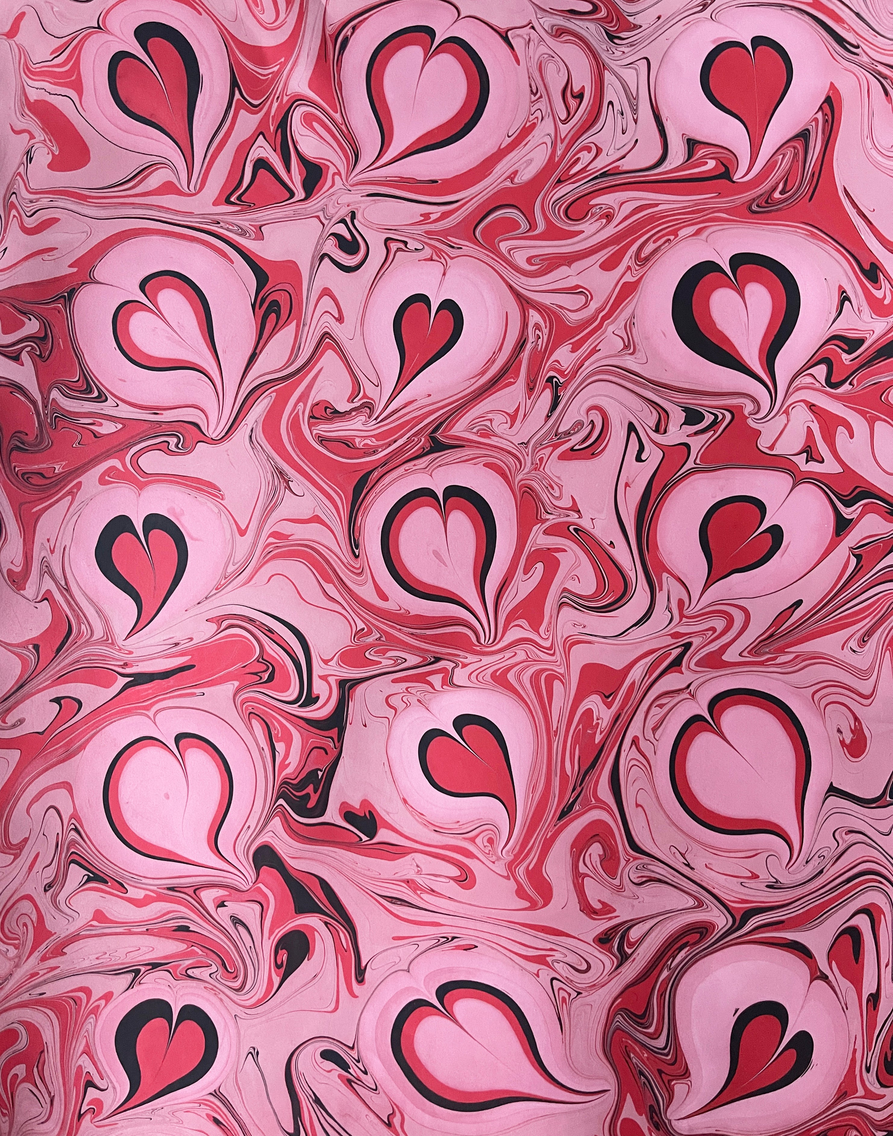 Marbled paper with heart shapes in pink, red, and black.