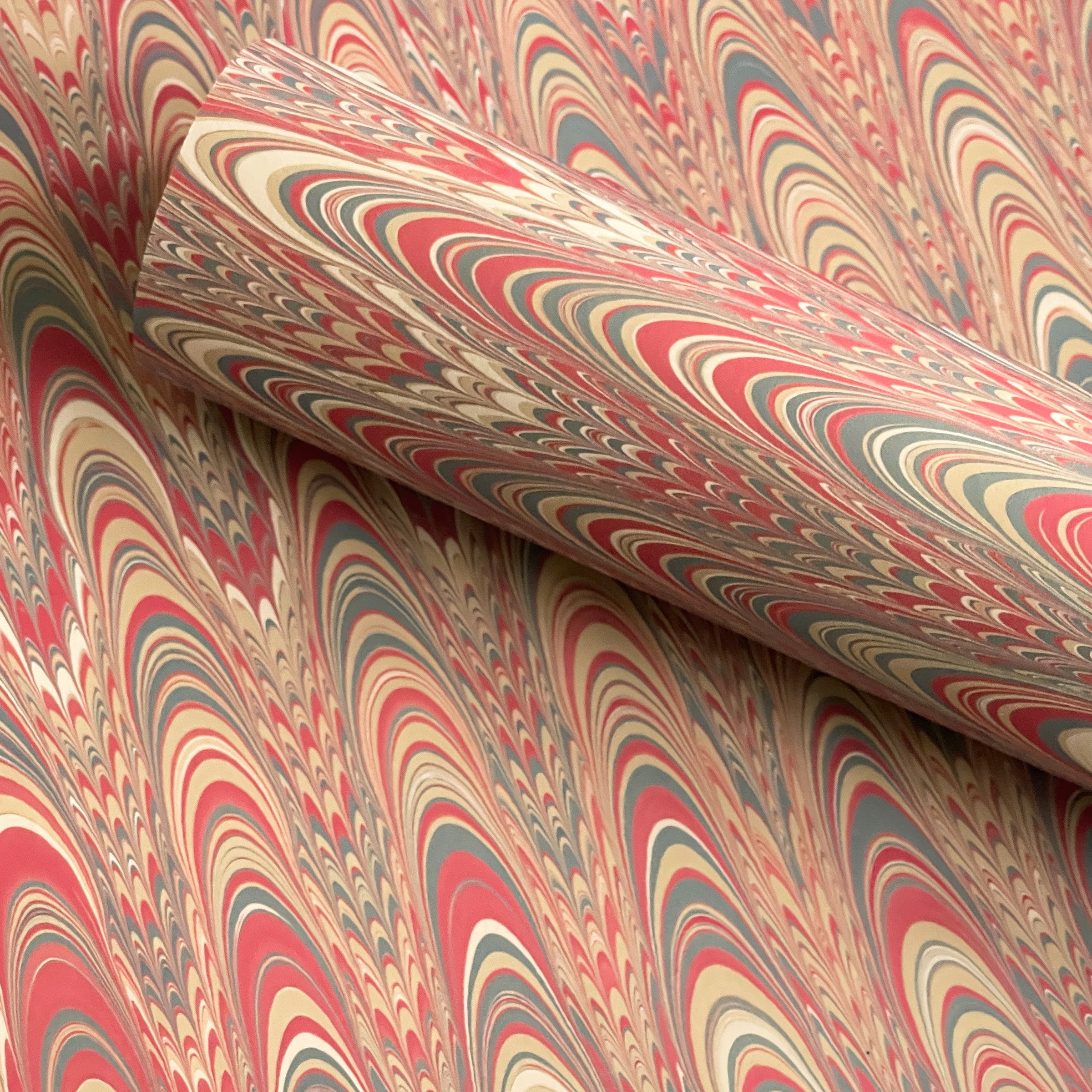 Marbled paper with terracotta red, beige, and gray swirls in a pattern known as Two Sisters