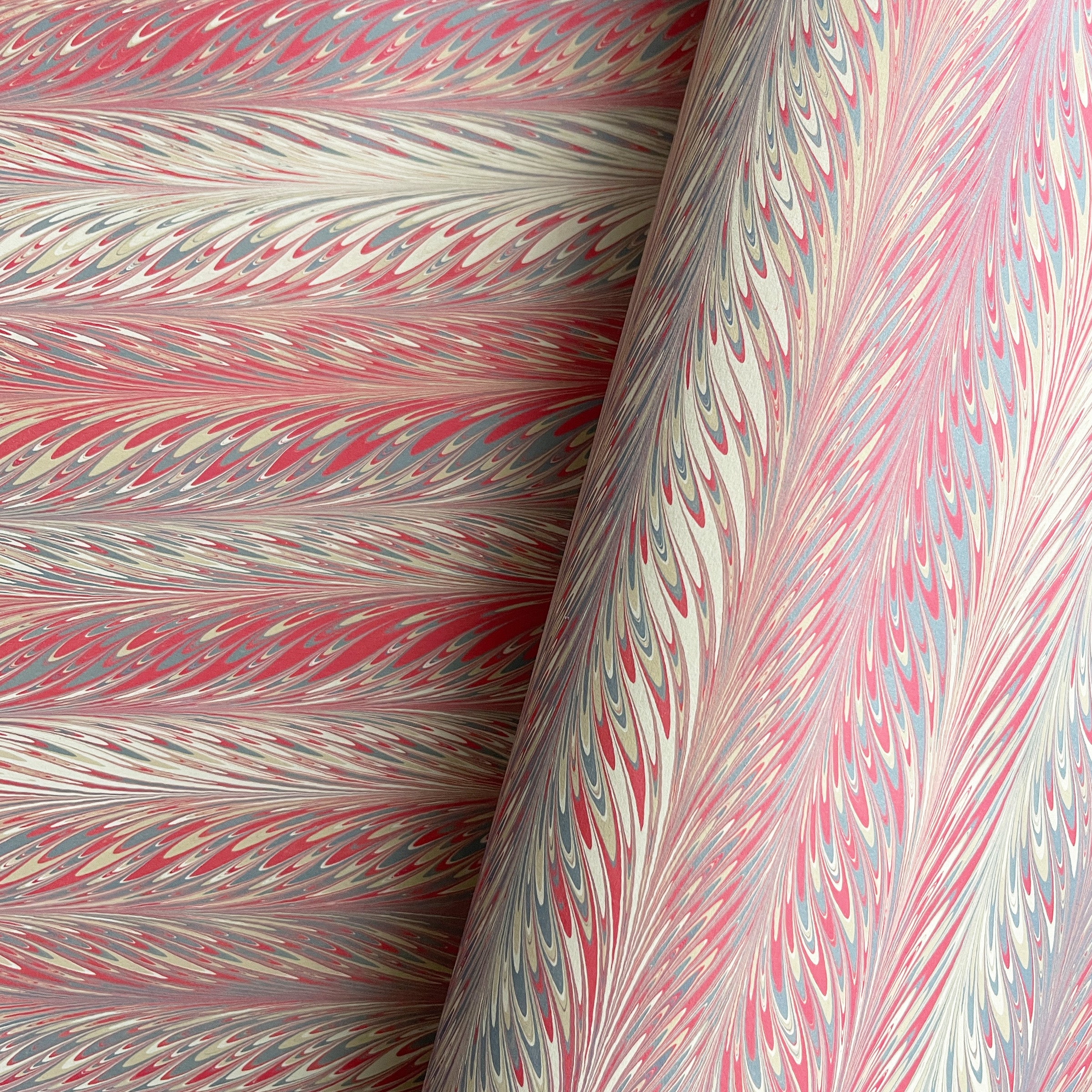 Marbled paper with a feathered design in salmon red, slate, and beige colors.