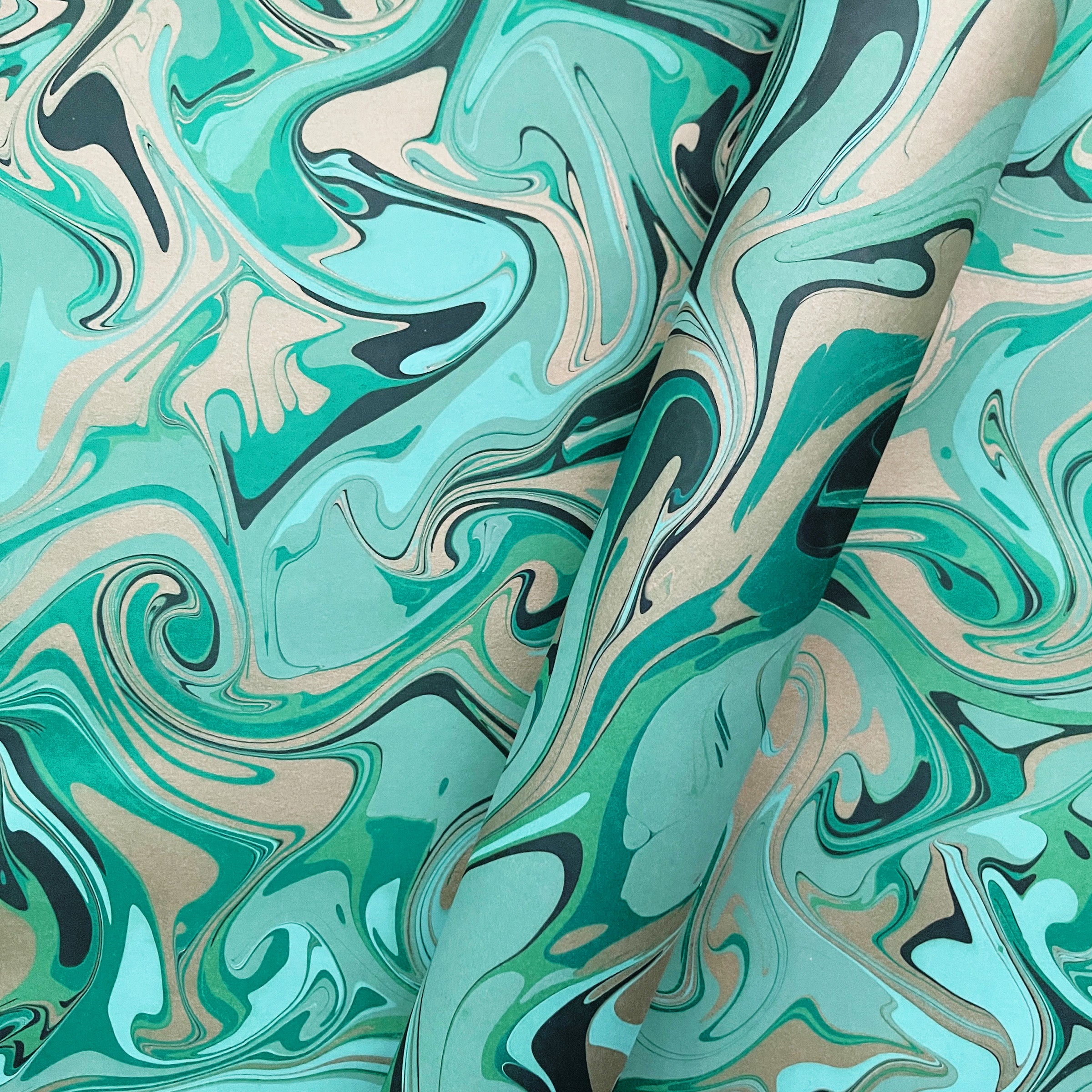 Marbled paper in a swirled organic pattern with green, black, and metallic gold swirls inspired by malachite stone.