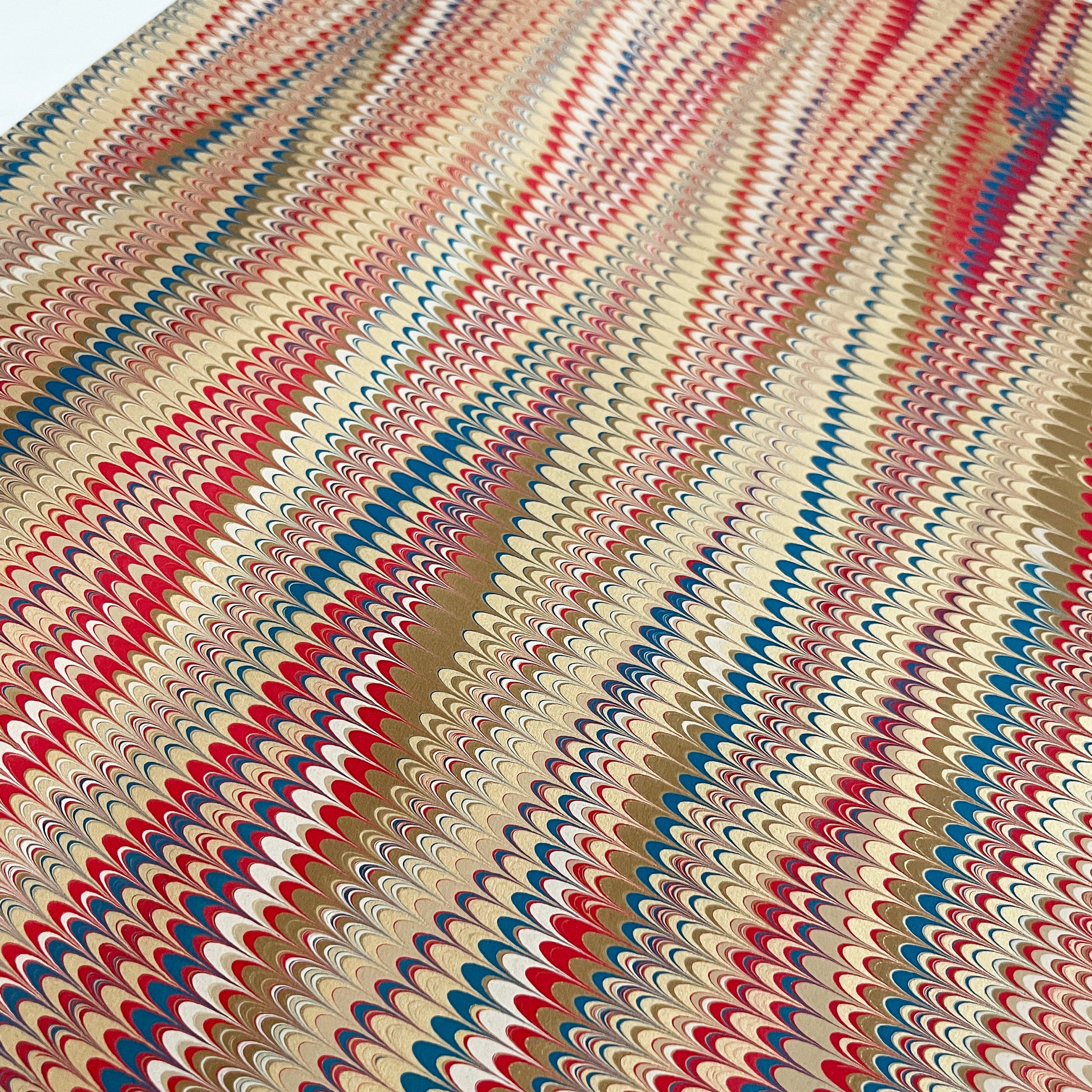 Hand marbled paper with red, blue, and beige colors