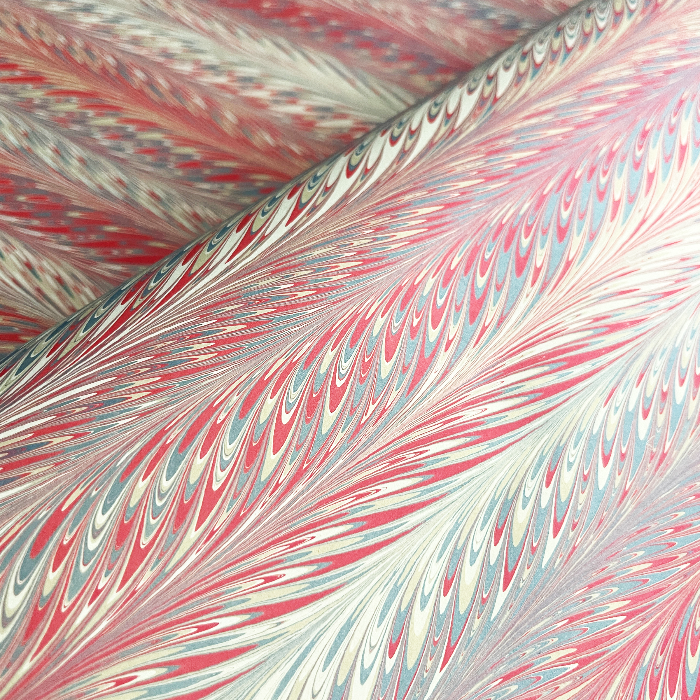 Marbled paper with a feathered design in salmon red, slate, and beige colors.