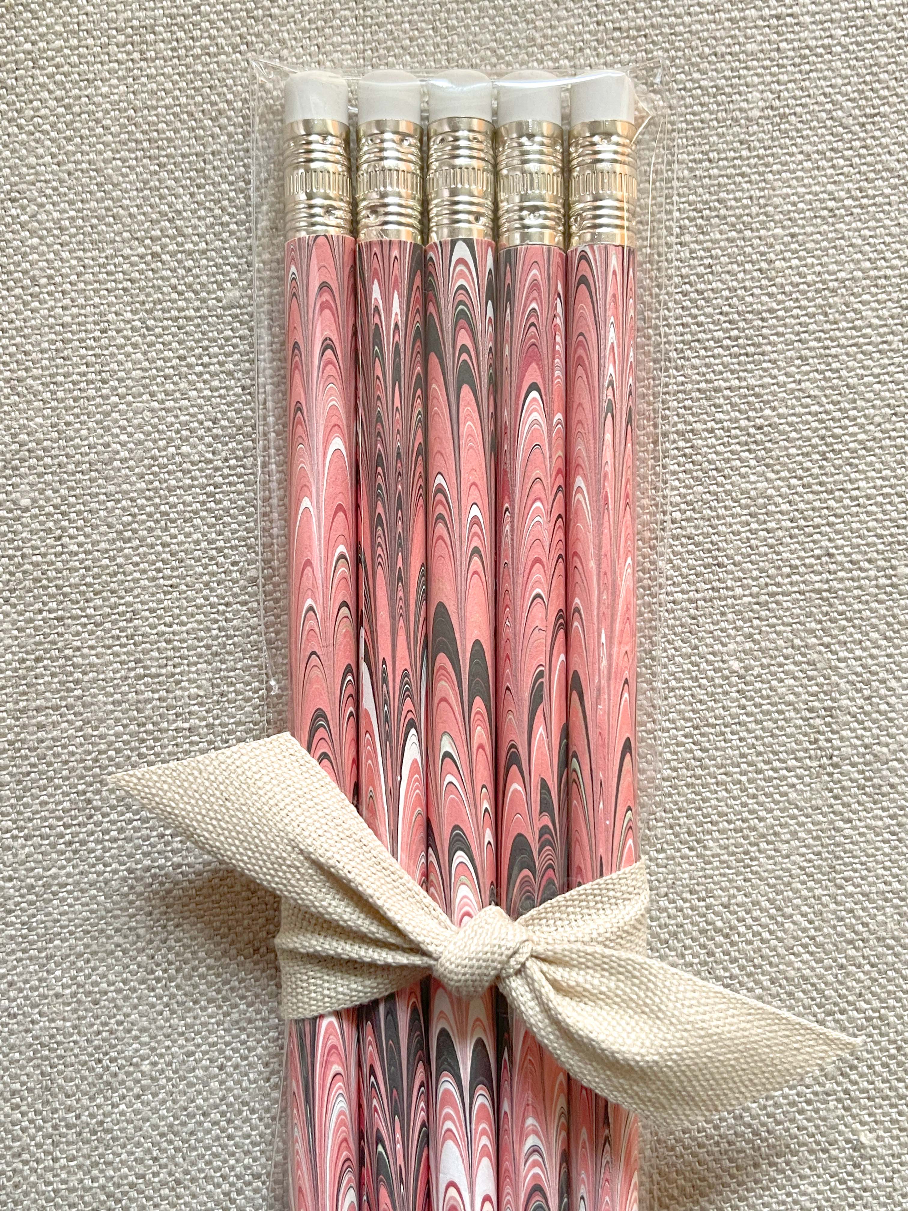 A set of five wooden pencils with a marbled paper design in pink and brown colors.