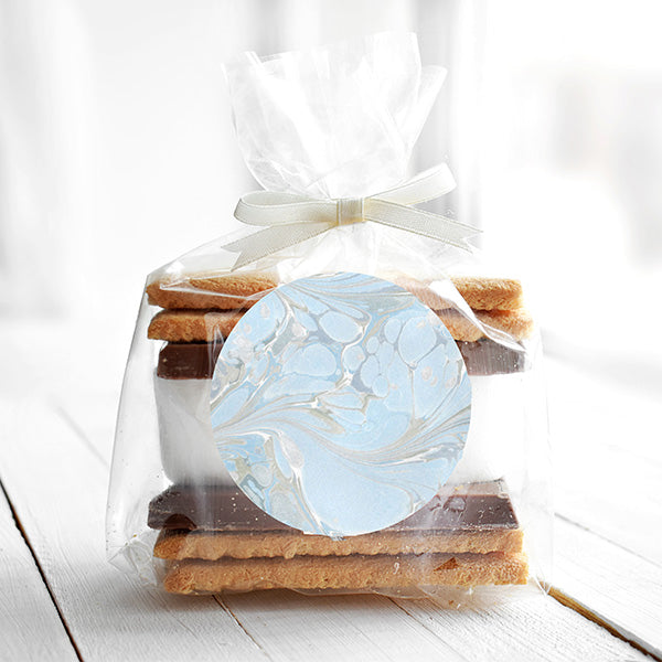 An individual clear bag filled with smores, a delectable dessert, adorned with a 3-inch 'Aquatic Elegance' sticker featuring an organic blue pattern.  The sticker adds an elegant touch to the sweet treats.